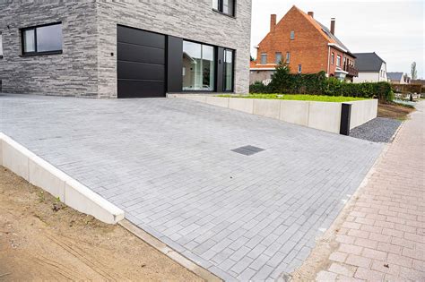 Foto van een oprit bestraat met tegels met facet, die de duurzaamheid en esthetiek van deze keuze benadrukt.