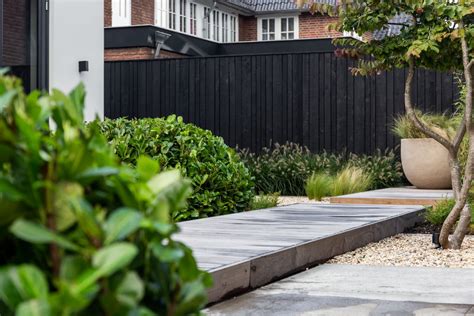 Voorbeeld van een moderne tuin met een aluminium schutting gecombineerd met beplanting.