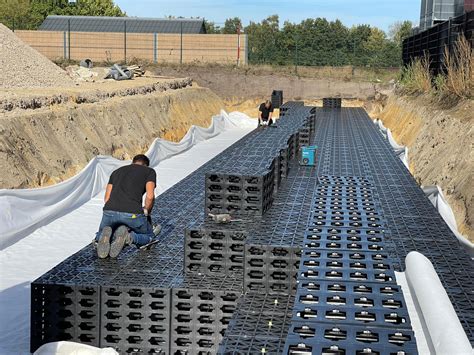 Detail van infiltratiekratten die in de grond zijn ingegraven en bedekt met geotextiel.