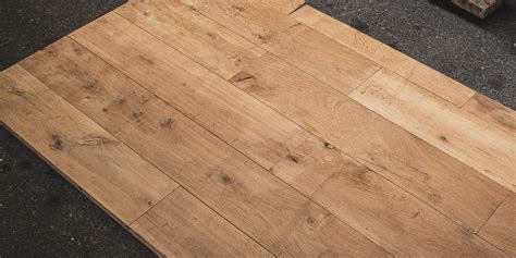 Illustratie van verschillende sorteringen massieve eiken vloerplanken, variërend van grof met grote noesten tot rustiek met kleine noesten.