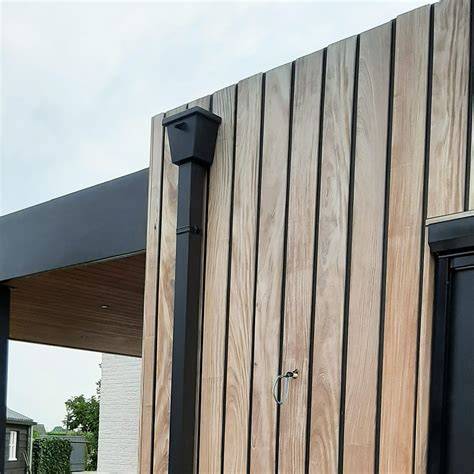 Donkergrijze aluminium regenpijp op gevel met bijpassende bevestiging