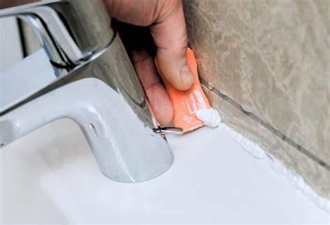 Detailfoto van het aanbrengen van kit langs de rand van een spoelbak