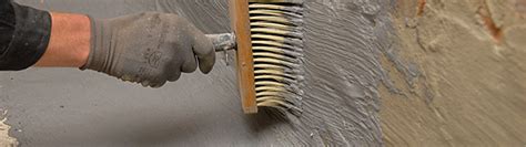 Detailopname van het aanbrengen van waterdichte cementlagen op een keldermuur.