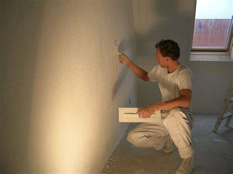 Tadeltakbeeld van een professionele stucadoor die aan een muur werkt met gereedschap, passend bij het vakgebied