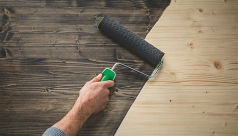 Gedetailleerde foto van het aanbrengen van verf op een houten plafondbalk met een kwast.