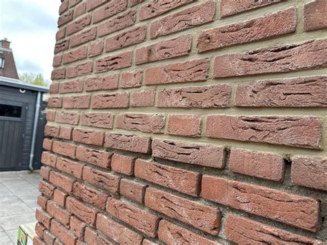Close-up van een gevel met zichtbare scheuren en slecht voegwerk