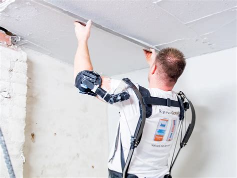Stukadoor die een exoskelet draagt tijdens werkzaamheden aan een muur.