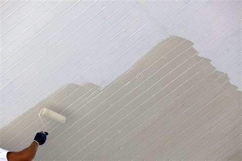 Een schilder die een muur streeploos saust met een roller