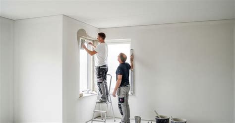 Twee stukadoors die samenwerken aan een muur