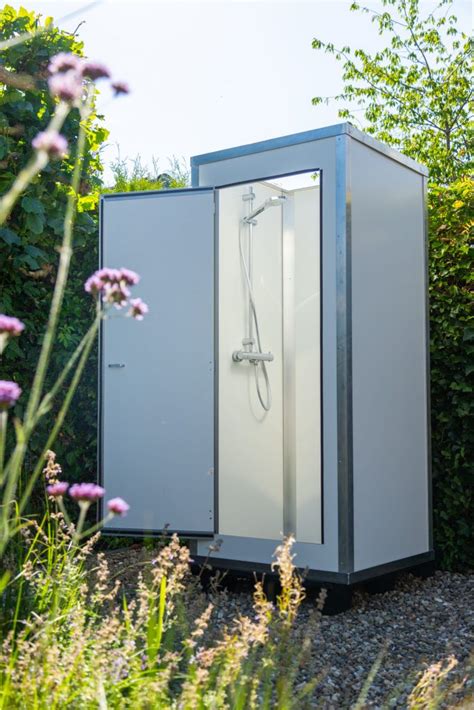 Illustratie van een moderne, compacte mobiele douchecabine, geplaatst in een tuin tijdens een huisverbouwing.