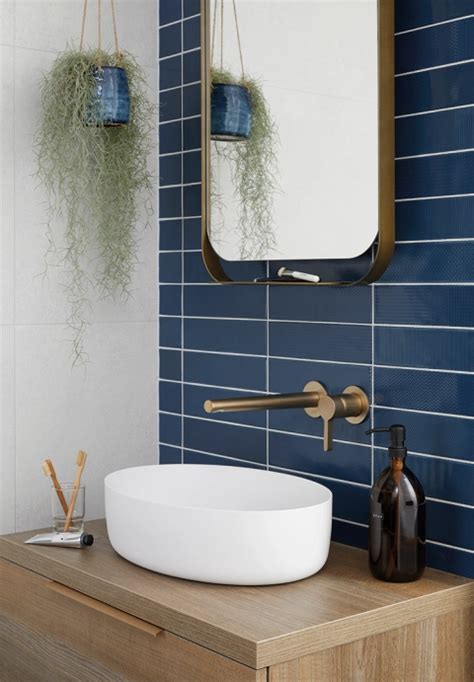 Een badkamer met blauwe tegels, gecombineerd met een houten wastafelmeubel en planten.