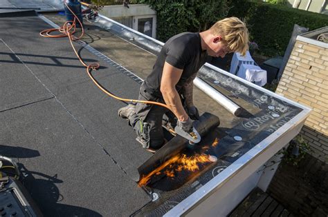 Afbeelding van een dakdekker die een plat dak inspecteert op vorstschade
