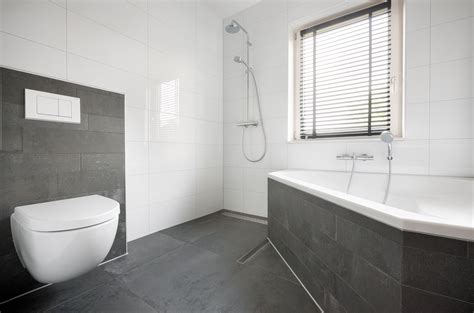 een moderne badkamer met antraciet wand- en vloertegels en zwarte kranen