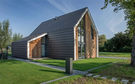 Galerij van schuurwoningen met zwarte houten planken aan de gevel, zowel verticaal als horizontaal geplaatst.