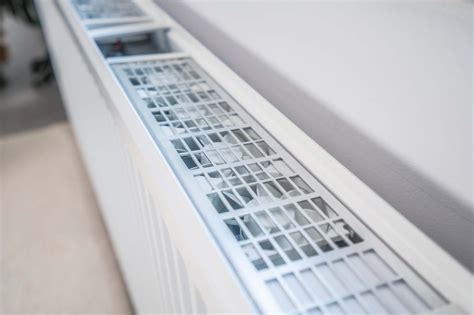 Een voorbeeld van een kleine radiator discreet geplaatst onder een raam in een compacte woonruimte.