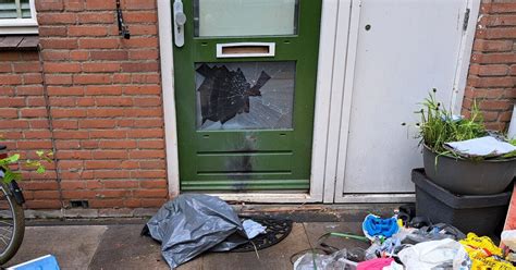 Beschadigde voordeur na explosie, zicht op beschadigd huis