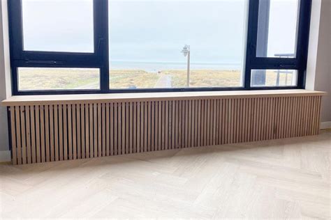 Detail van een radiatorombouw met een geïntegreerd knopluikje voor radiatorbediening.