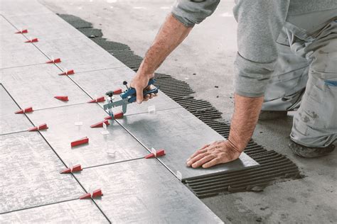 Gedetailleerde afbeelding van een tegelzetter die tegels aanbrengt op een cementdekvloer.