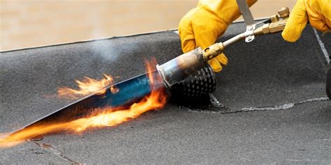 Foto van een dakdekker die bitumen aanbrengt met een brander
