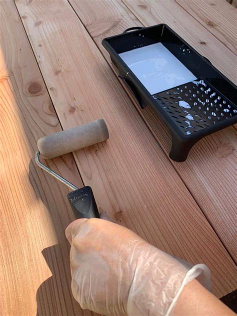 Afbeelding van iemand die hout aan het impregneren is met een kwast.