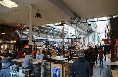 interieur Foodhallen met lange tafels en diverse stands