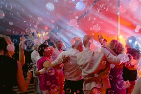 Een bruiloftsfeest in volle gang, met gasten die dansen en lachen onder discoballichten.