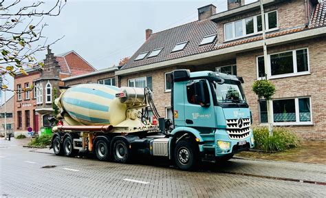 Foto van vrachtwagens die zand en grind leveren in een woonwijk.