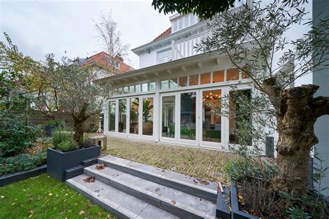 Illustratie van een klassieke serre aan een jaren '30 woning, met harmonicadeuren en lichtstraat.
