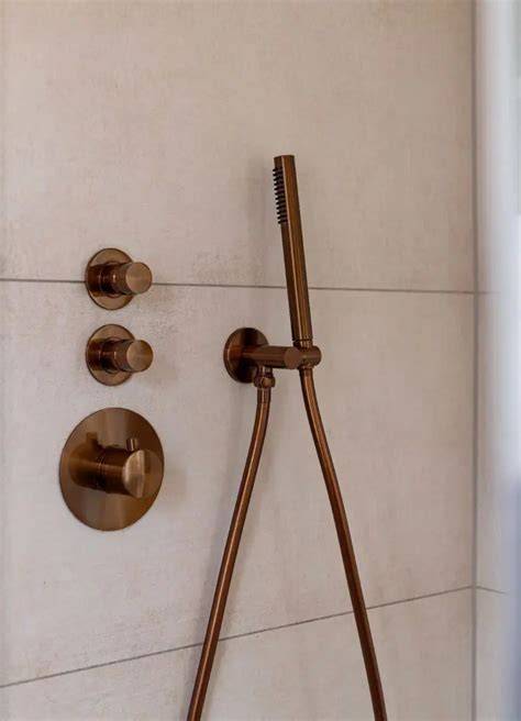 Beige marmerlook tegels gecombineerd met koperen kranen