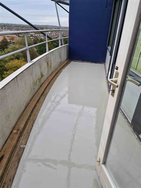 Detailopname van een slecht uitgevoerde dekvloer op een balkon met zichtbare scheuren.