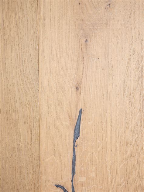 Close-up van een naturel eiken laminaatplank met zichtbare noesten en V-groeven