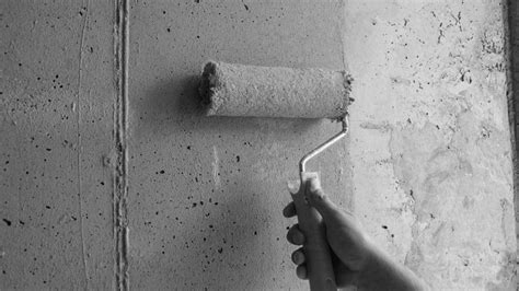 Close-up van een stukadoor die een muur voorstrijkt met een roller