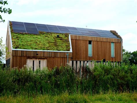 Foto van een huis met een groendak en zonnepanelen.