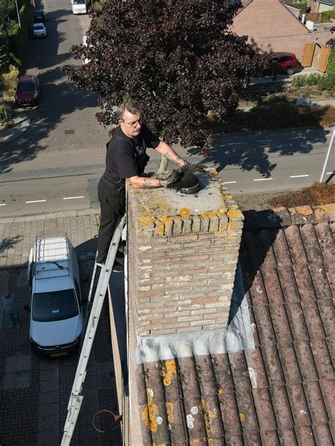 Schoorsteenveger aan het werk met borstel en ladder