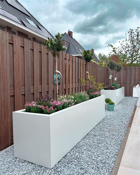 Een schutting versierd met diverse plantenbakken en hanging baskets