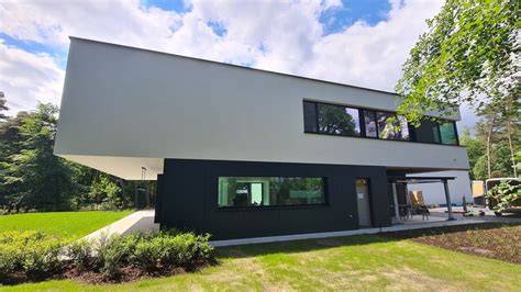 Voorbeeld van een lamellengevel met wit paneel en donkere kozijnen in moderne architectuur