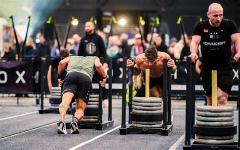 Atleten die de Sled Push uitvoeren tijdens een HYROX wedstrijd