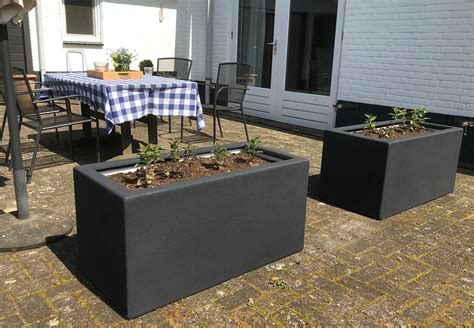 Afbeelding van een gestucte betonnen plantenbak met RVS hoeklijsten