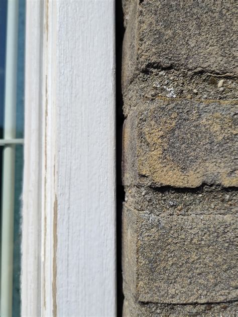 close-up van compriband dat uitzet in een kier tussen muur en kozijn
