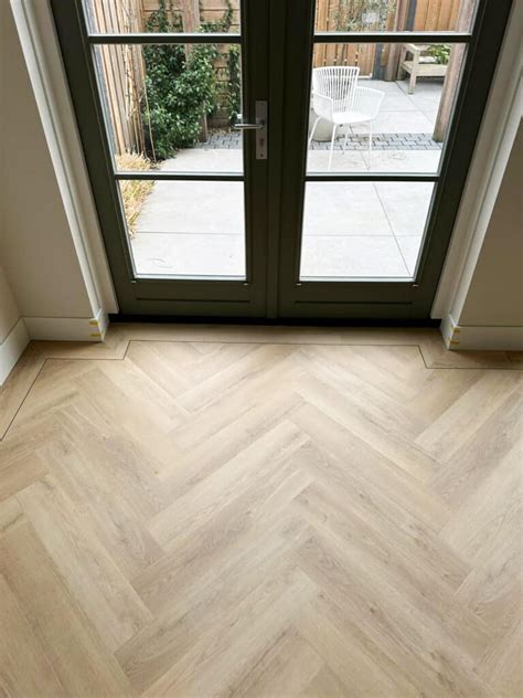 Illustratie van een visgraat vloer met een duidelijke band en een smalle zwarte bies langs de muur.