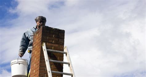 Foto van een vakman die voegwerk aan een schoorsteen herstelt