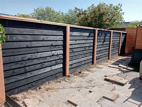 Illustratie van een Zweeds Rabat schutting met zowel naturel als zwarte planken.