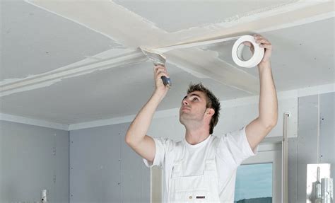 Detail van het aanbrengen van papierband in een inwendige gipsplaat hoek, met een troffel en plamuurmes.