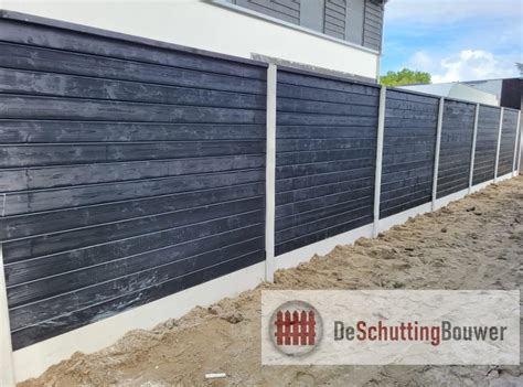 Gedetailleerde weergave van een zwarte blokhutprofiel schutting met witte betonpalen, die het contrast benadrukt.