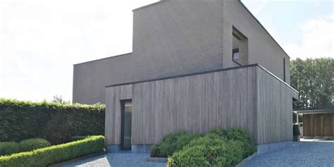 Afbeelding van kwasten en potten met buitenbeits naast houten latten