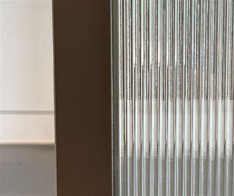 Detail van een stalen douchewand met geribbeld glas voor extra privacy