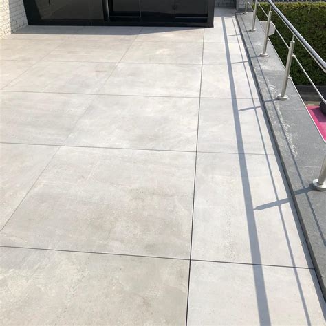 Een voorbeeld van een stijlvol gelegd terras met grijze HKC kunststof terrastegels in een modern patroon.