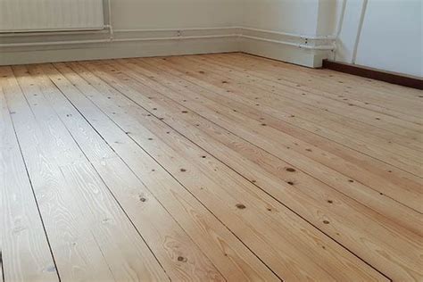 Gedetailleerde foto van een onbehandelde grenen vloer met zichtbare houtnerf en noesten.