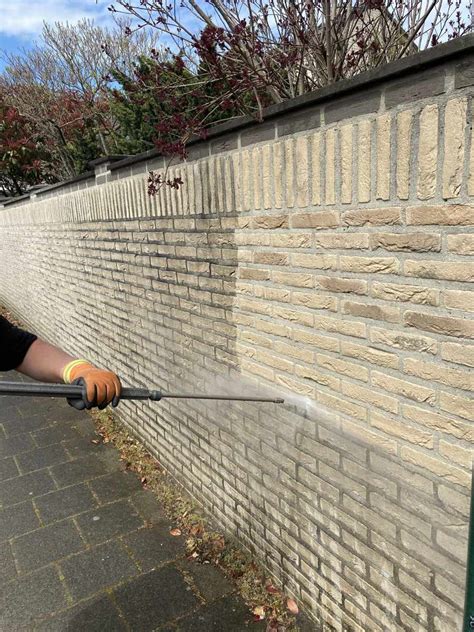 Schilder die een gevel reinigt met een hogedrukreiniger.