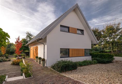 Foto van de Dijkwoning Rottekade, met een moderne uitstraling door de combinatie van gevelstucwerk, houten geveldelen en een stalen dak.